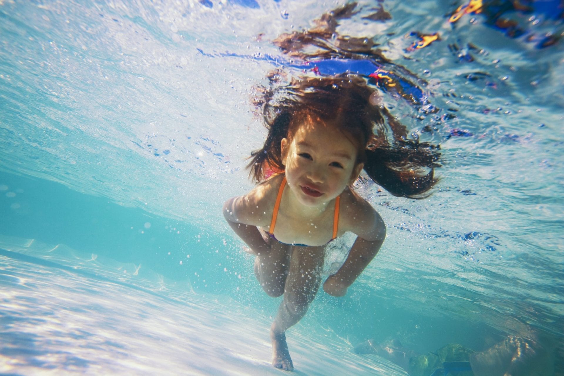 A girl swimming in a pool after having pool leak detection services in Naples, FL